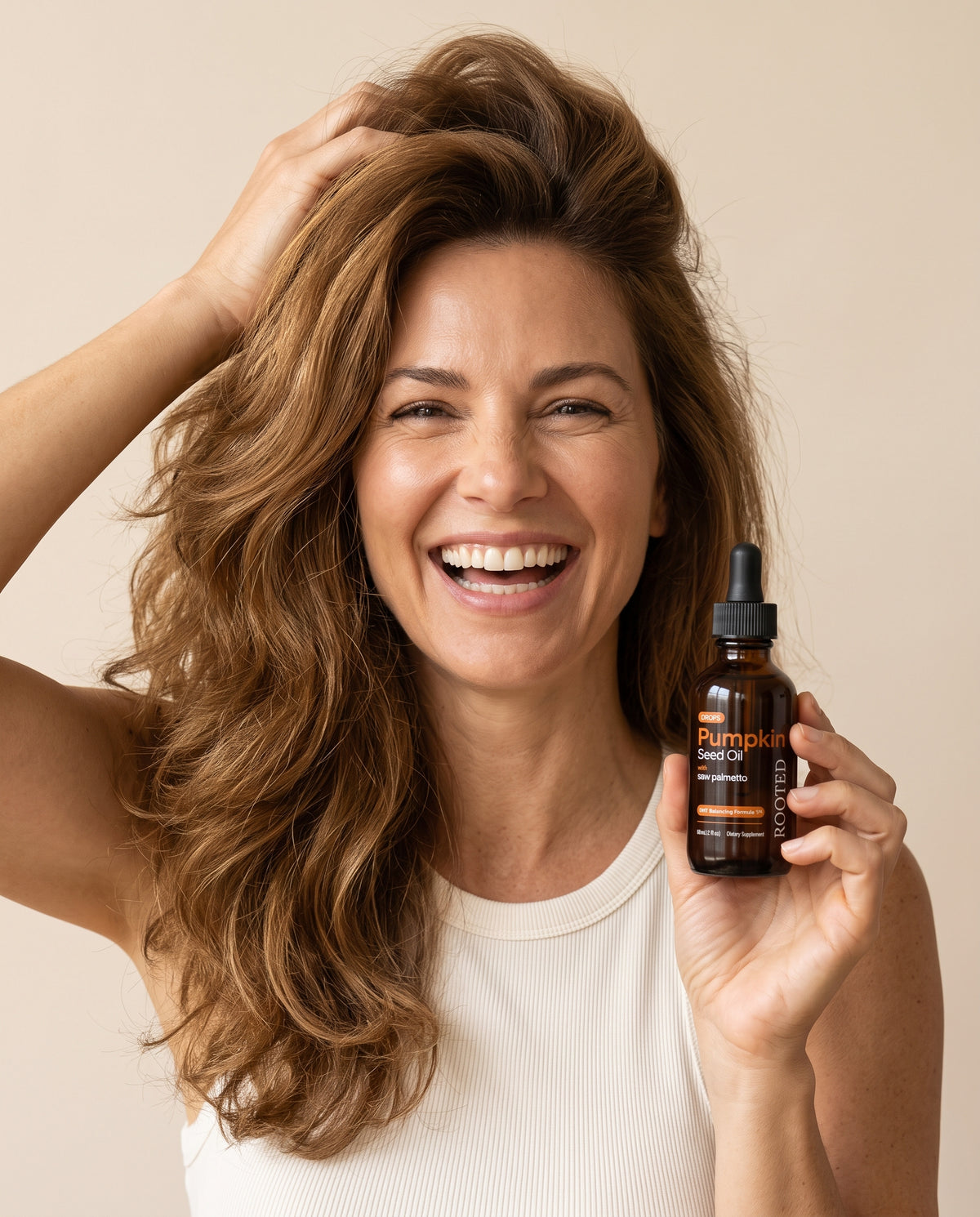 Laughing woman with thick, full hair holding a bottle of Rooted drops